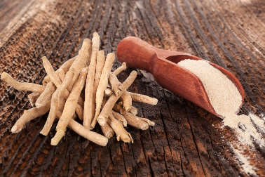 Ashwagandha root and ashwagandha root powder in a scoop on a wooden table